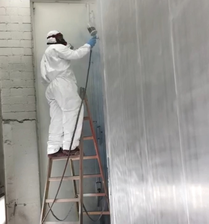 Een man op een ladder die een coating aanbrengt