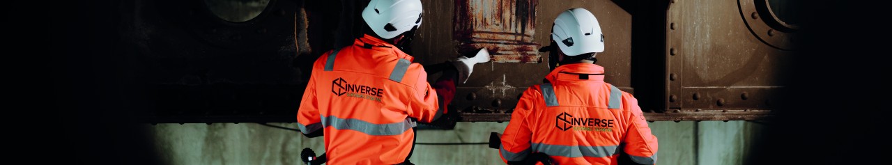 Twee medewerkers van InVerse verwijderen coating van een van de loggers van de Waalbrug