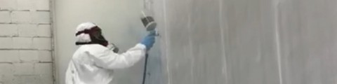 Een man op een ladder die een coating aanbrengt