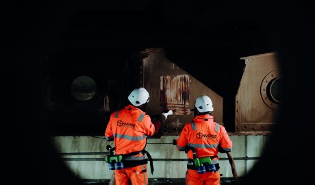 Twee medewerkers van InVerse verwijderen coating van een van de loggers van de Waalbrug